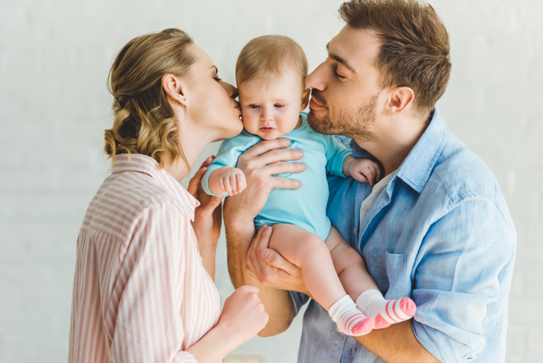 Parents kissing little daughter and holding her in hands - Fotografie, Obrázek
