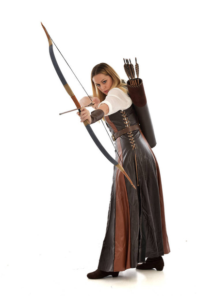 Ganzkörperporträt einer Frau im braunen mittelalterlichen Fantasiekostüm mit Pfeil und Bogen. stehende Pose auf weißem Studiohintergrund. - Foto, Bild