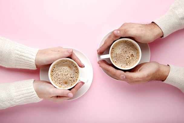 weibliche und männliche Hand mit Kaffeebechern auf rosa Hintergrund - Foto, Bild