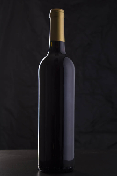 Isolated Red Wine Bottle in a Black Background - Фото, зображення