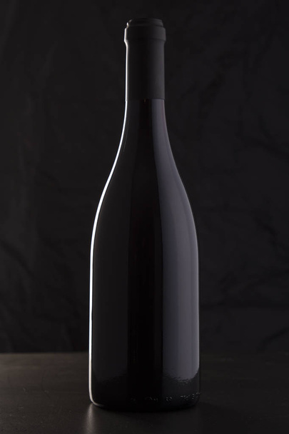 isolierte Rotweinflasche vor schwarzem Hintergrund - Foto, Bild