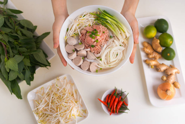 Női szakács elkészíteni a hagyományos vietnami leves Pho bo gyógynövények, hús, rizs tésztával - Fotó, kép