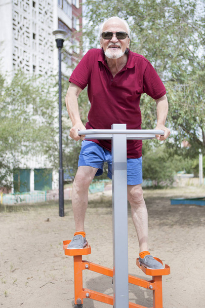 Un senior s'entraîne sur des équipements sportifs en plein air
 - Photo, image
