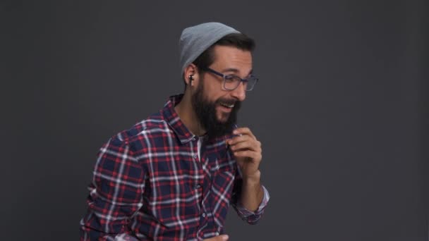 Hipster πρόσωπο με ακουστικά χρησιμοποιώντας το κινητό τηλέφωνο  - Πλάνα, βίντεο
