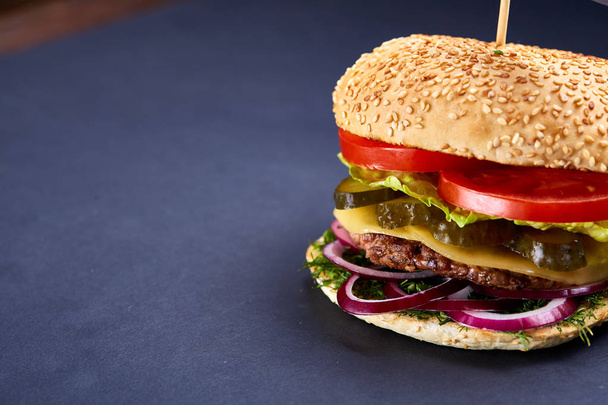 Klassieke Amerikaanse cheeseburger met zwarte vlag op de top over de donkere achtergrond, close-up, selectieve aandacht - Foto, afbeelding