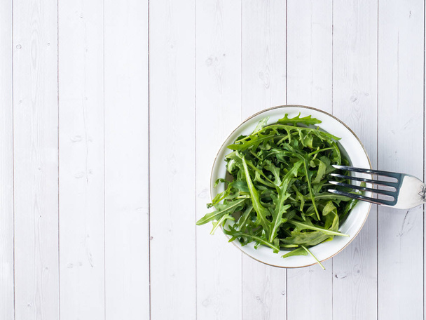 Dietary salad of arugula leaves in plate and white background - Photo, image