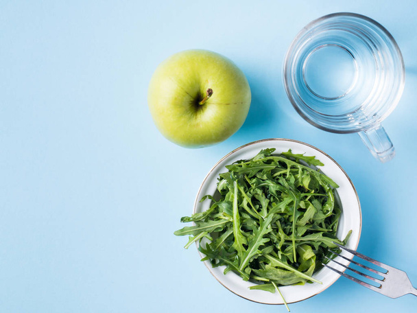 Dieta foglie insalata verde mela un bicchiere d'acqua su sfondo blu
 - Foto, immagini