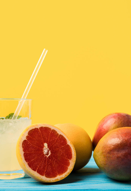 vista de cerca de cóctel de verano fresco y frutas tropicales maduras en amarillo
 - Foto, Imagen