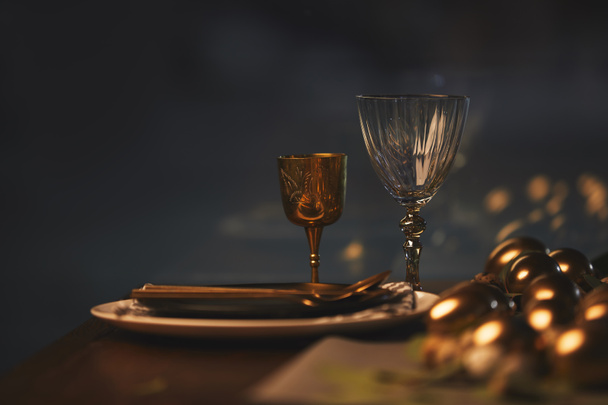 glazen met platen en gouden paaseieren op tafel - Foto, afbeelding