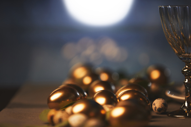 close up of golden easter eggs and glass on table - Foto, immagini
