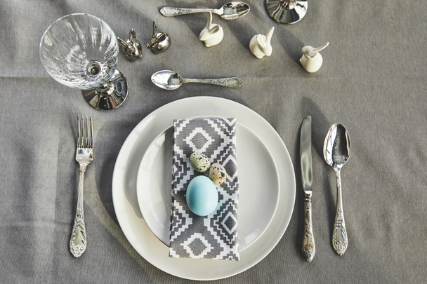 вид сверху на окрашенное голубое куриное яйцо на тарелках на праздничном столе
 - Фото, изображение