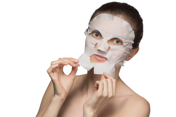 Beautiful young woman is applying a cosmetic mask on a face on a - Photo, Image