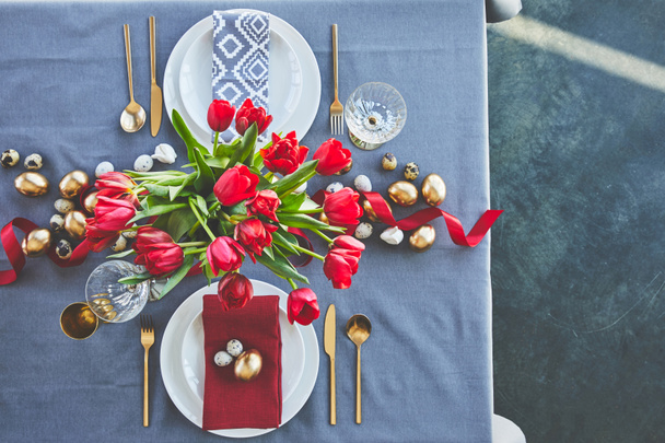 top view of bouquet of red tulips and easter eggs on festive table  - Foto, Bild