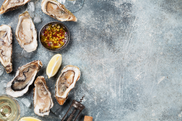Verse oesters en witte wijn op stenen tafel. Bovenaanzicht met ruimte  - Foto, afbeelding