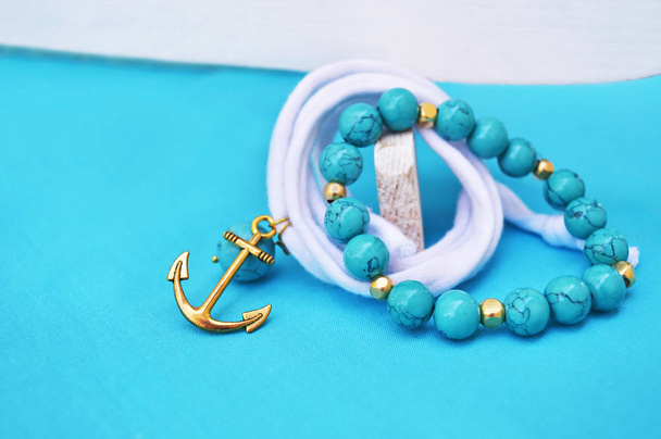 pulsera de piedras preciosas de color turquesa - joyas náuticas con ancla de oro - fondo turquesa
 - Foto, imagen