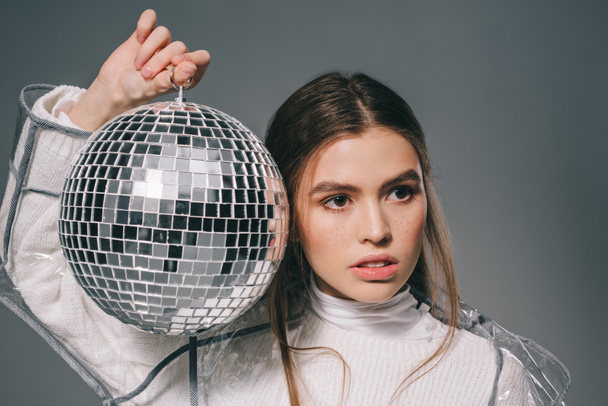 portrait of young fashionable woman with disco ball in hands isolated on grey - Foto, Imagen