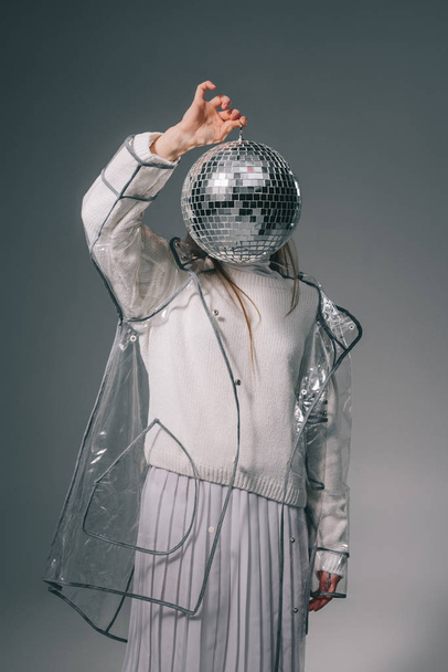 obscured view of stylish woman covering face with disco ball isolated on grey - Φωτογραφία, εικόνα