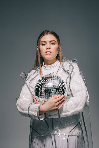 portrait of stylish young woman with disco ball in hands isolated on grey - Fotó, kép