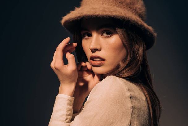 portrait of beautiful young woman in stylish hat looking at camera isolated on black - Foto, Imagem