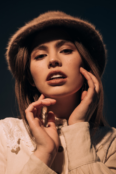 portrait of beautiful young woman in stylish hat looking at camera isolated on black - Fotografie, Obrázek