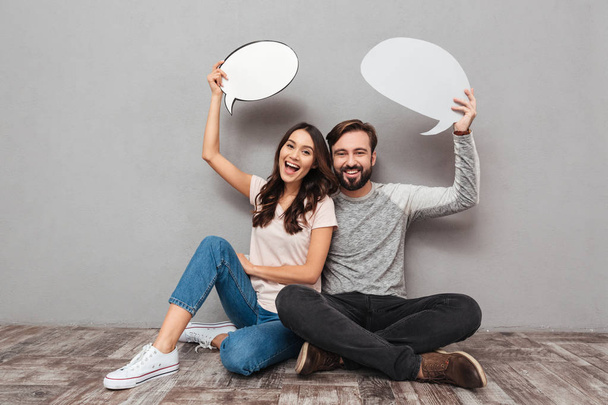 Smiling handsome man with his wife holding speech bubbles. - 写真・画像