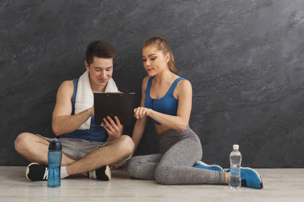 junges Paar diskutiert Trainingsplan im Fitnessstudio - Foto, Bild