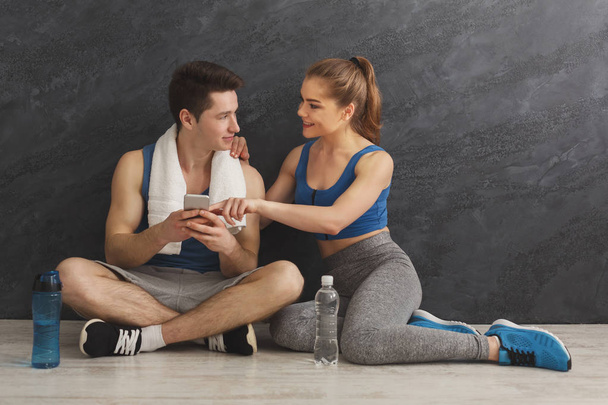 Young couple discussing workout plan at gym - Foto, Imagem