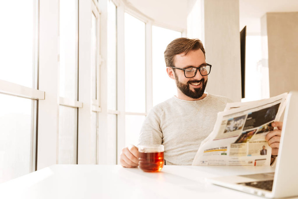 Cheerful european bearded man wearing glasses sitting at table a - 写真・画像