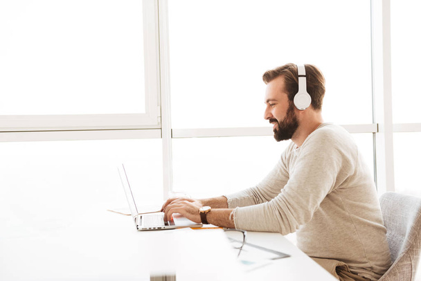 Image in profile of modern guy 30s using white headphones and co - Photo, Image