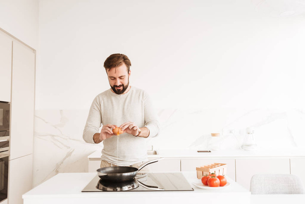 Photo of european man with short brown hair and beard cooking om - Fotó, kép