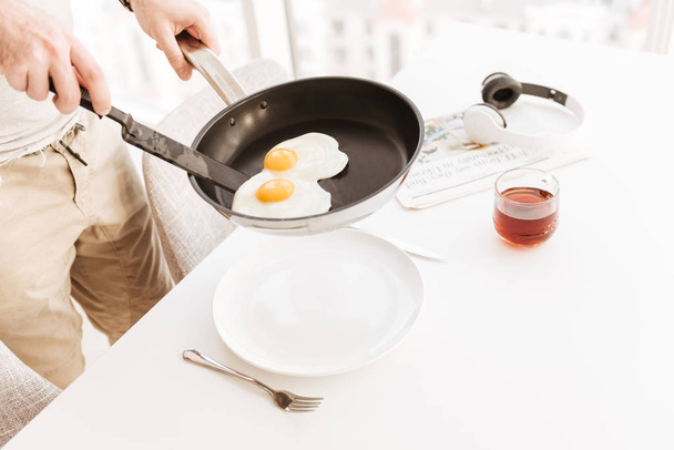 Cropped photo of man in casual clothing putting frying eggs into - Photo, Image