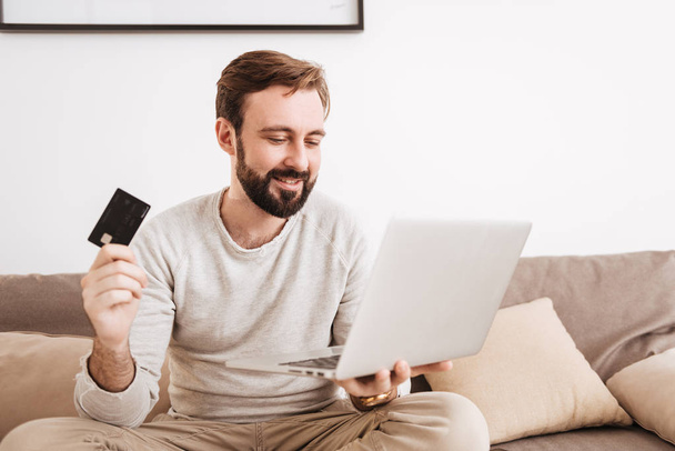 Portrait of a happy man shopping online with credit card - Foto, Imagen