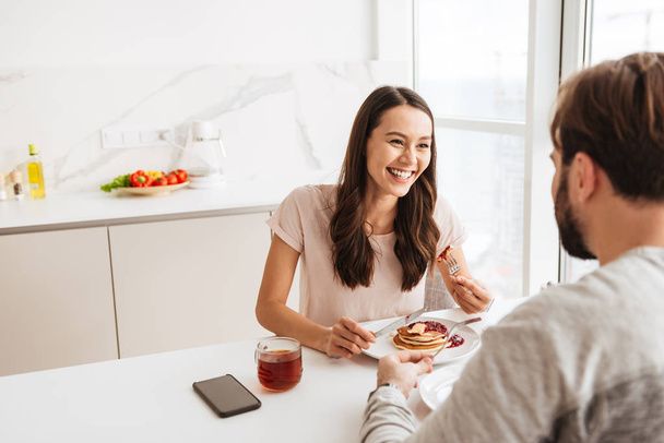 Laughing young couple having breakfast - Фото, зображення