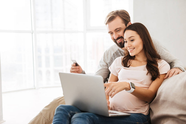Portrait of a smiling young pregnant couple shopping online - Foto, Imagen