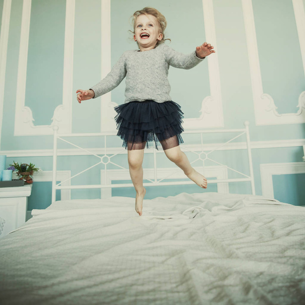 happy five year old girl jumping on the bed - 写真・画像