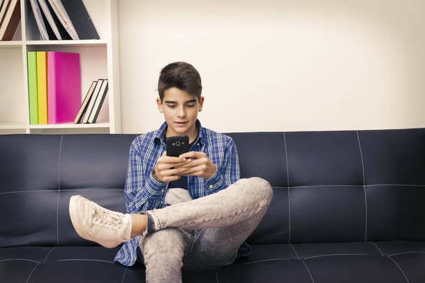дети, подростки или подростки с мобильным телефоном, сидящим на диване
 - Фото, изображение