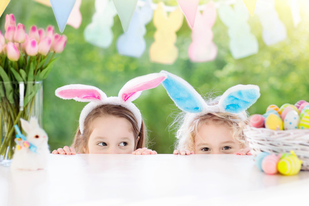 Kinder mit Hasenohren und Eiern auf Ostereiersuche.  - Foto, Bild