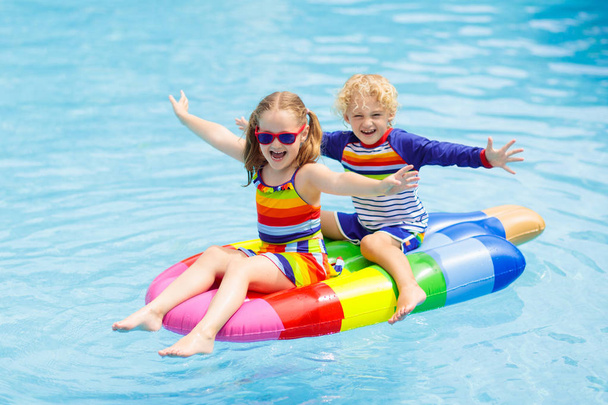 Kinderen op opblaasbare float in zwembad.  - Foto, afbeelding