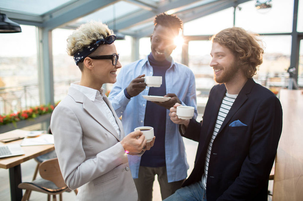 Trzech kolegów spokojny o herbatę lub kawę a spędzanie czasu w café według konwersacji - Zdjęcie, obraz