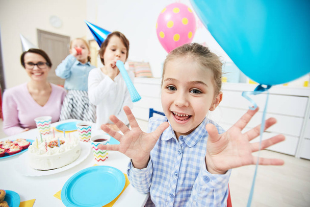 Cute little child expressing gladness while having fun by festive table in kindergarten - Photo, Image