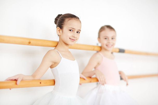 Happy mała dziewczynka i jej przyjaciel stojących drewnianych barów podczas treningu w balet Klasa - Zdjęcie, obraz