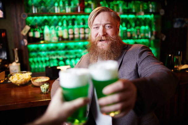 Homem barbudo feliz brindando com seu amigo no pub irlandês no dia de São Patrício
 - Foto, Imagem