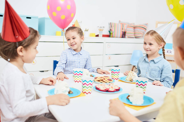 Grupo de crianças felizes desfrutando de jantar de aniversário e sobremesas no jardim de infância
 - Foto, Imagem