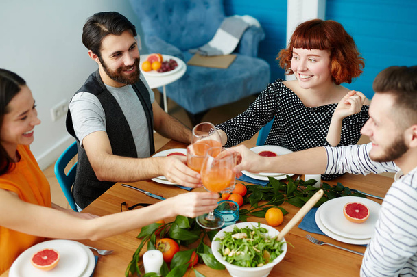 Deux couples heureux griller avec des verres de jus sur la table servie avec des aliments sains
 - Photo, image