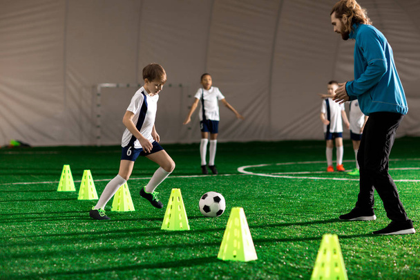 Молодий тренер і команда маленьких хлопчиків грають або тренуються на зеленому газоні
 - Фото, зображення