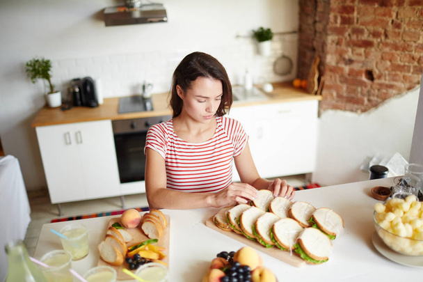 Attraente giovane donna mettendo panini fatti in casa in due file su tavola di legno
 - Foto, immagini
