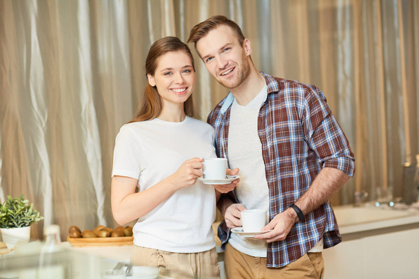 Souriant jeune couple passer du temps dans la cuisine par une tasse de thé ou de café
 - Photo, image