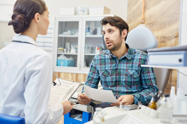 Beszélgetni fiatal orvos, a modern klinikák találkozó során férfi beteg - Fotó, kép
