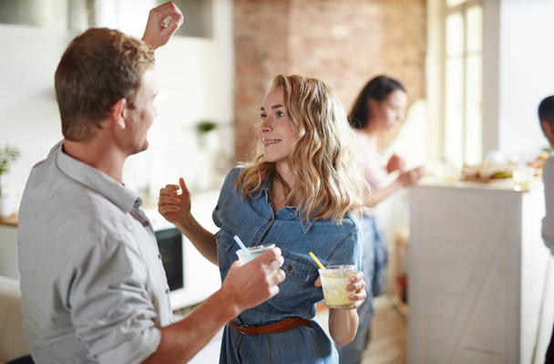 Young amorous couple with drinks dancing at home party with their friends on background - Photo, Image