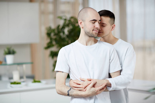 Affectionate young men standing in embrace while staying at home - Fotografie, Obrázek